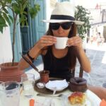 Thedi, founder of Path Travel Designs sipping coffee in a village on a Greek Island, where the path story begun.